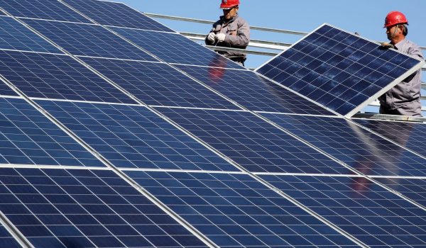 Workers install solar panels at a residential home in a village in Dongying